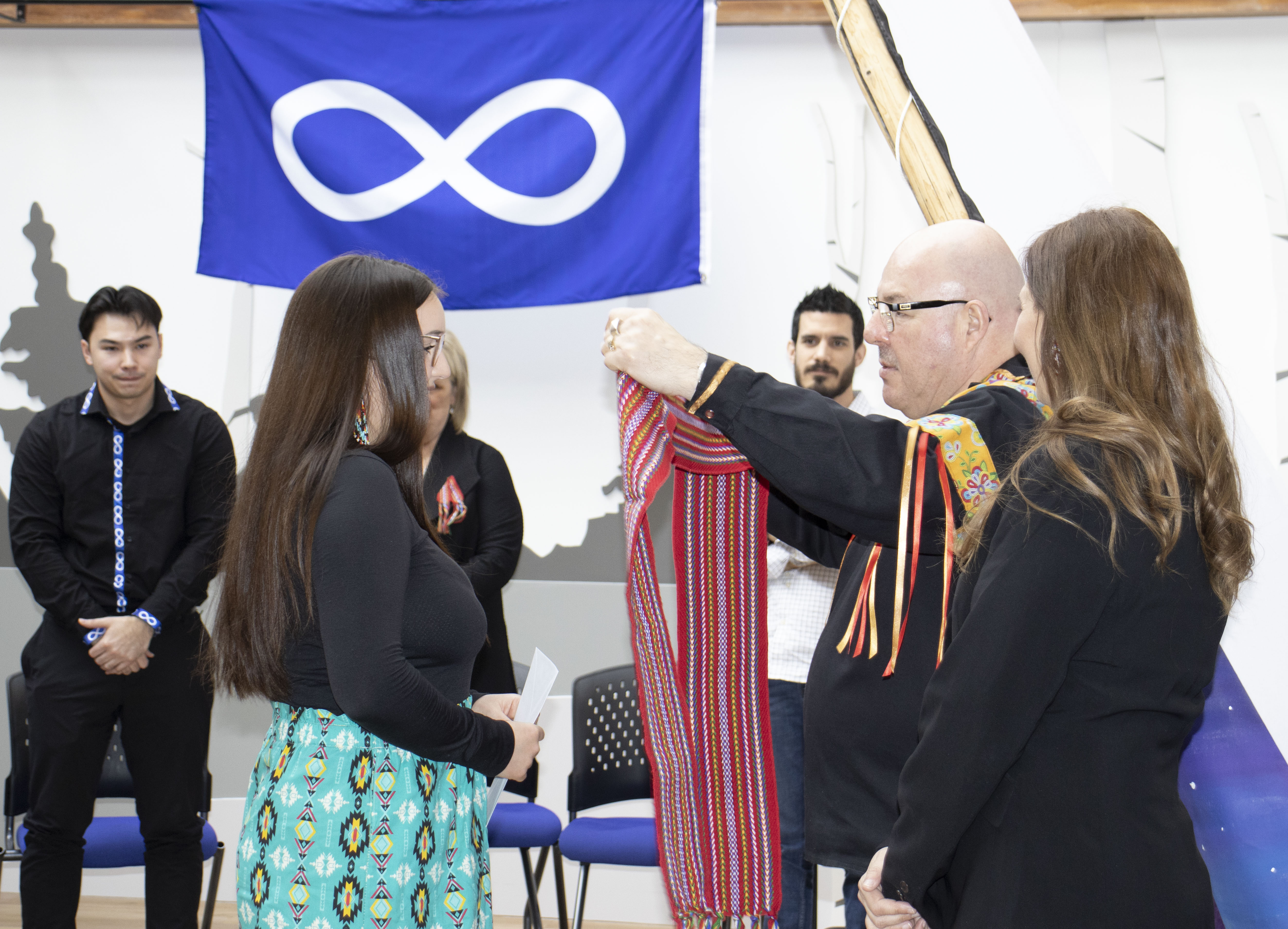 Métis knowledge keeper Dan Cardinal presents a Métis sash to award recipient 