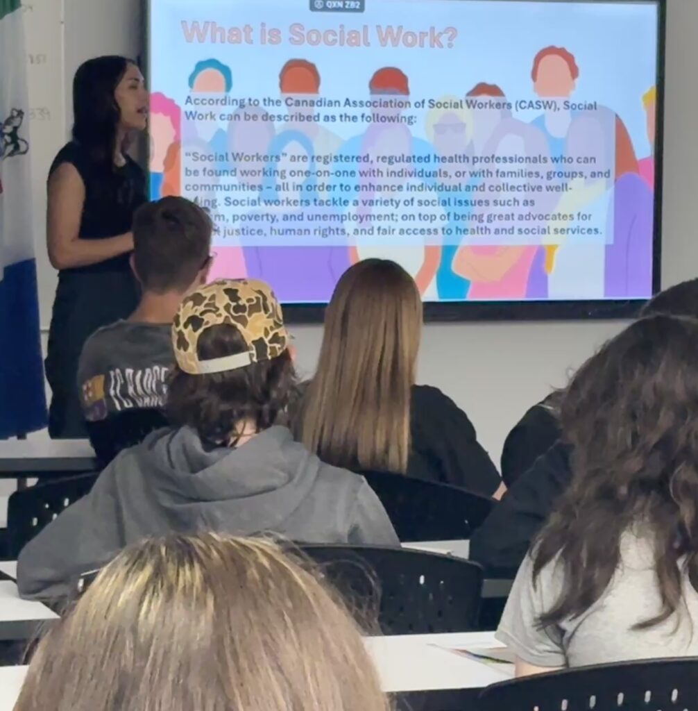 IMG_2408 - Portage College Instructor presenting a slide titled'What is Social Work?' to a classroom audience of students.