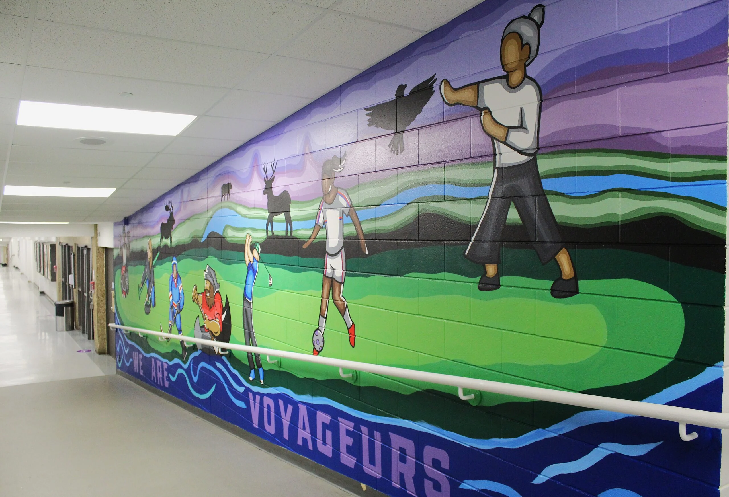 Voyageurs - Portage College Colorful hallway mural showing cartoon athletes playing sports against a purple sky and green hills, with the word VOYAGERS along the bottom edge.